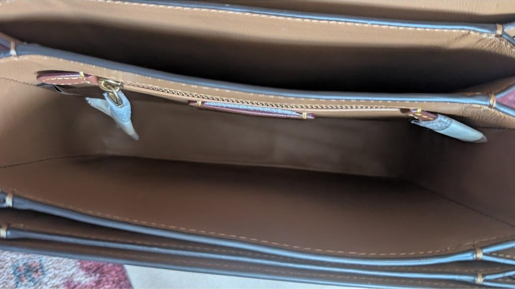 Close-up of the interior of a brown leather handbag, showing the tan lining, gold-tone zipper, and light blue trim along the edges. Pre-Owned Coach Tom Wesselmann Rogue Top Handle Bag
