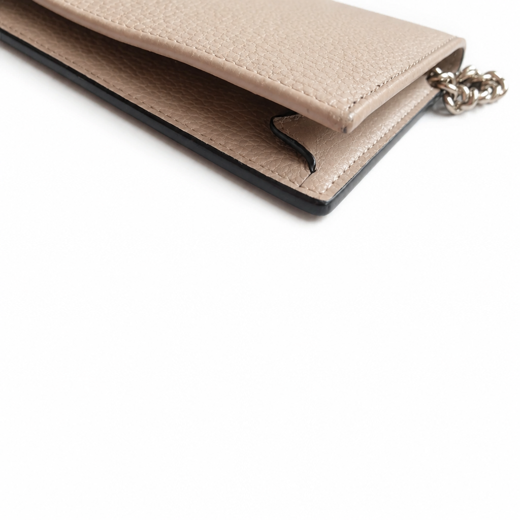 Close-up of a beige pebbled leather clutch or wallet with a black edge trim and a silver chain detail, photographed on a white background. Pre-Owned Gucci Interlocking G Chain Wallet / Crossbody – Beige Pebbled Leather