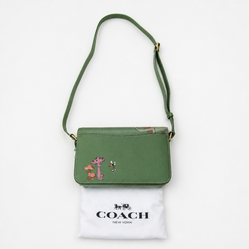 A green Coach crossbody bag with a small embroidered character patch, displayed above its white Coach New York dust bag on a clean white background. Pre-Owned Coach x Disney Tabby Shoulder Bag – Mickey Mouse – Green – Limited Edition