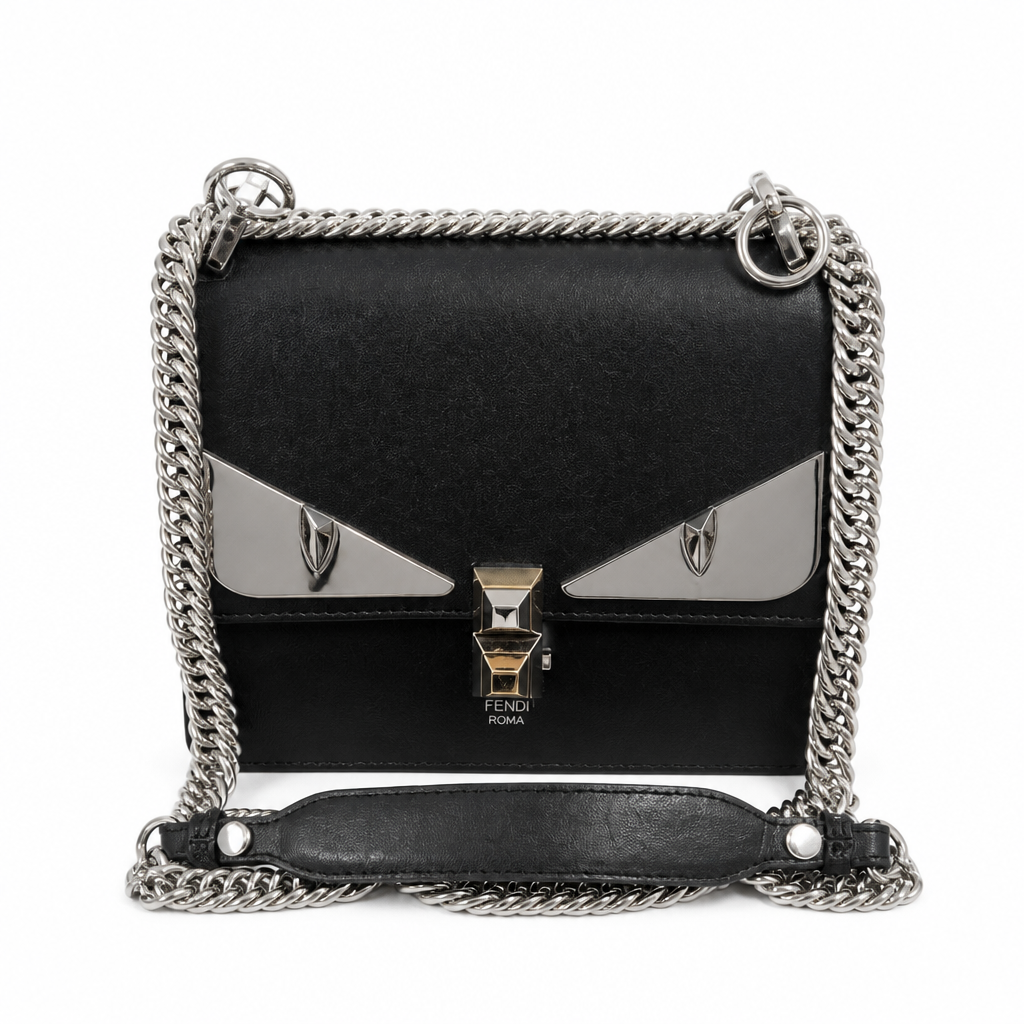 A black leather shoulder bag with a silver-tone chain strap and a distinctive metallic silver and gold 'eyes' design on the front flap, with 'Fendi Roma' printed below the clasp. Pre-Owned Fendi Kan I Monster Eyes Black Leather Chain Shoulder Bag