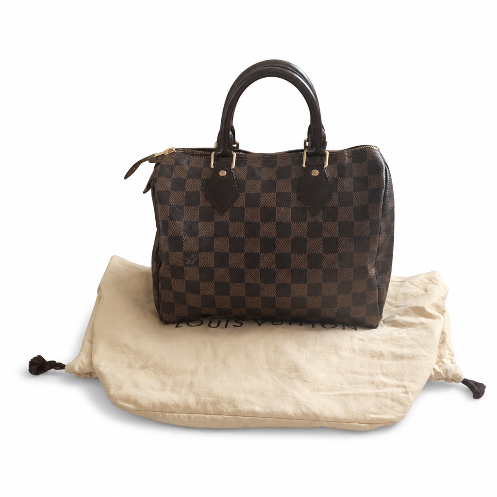 A Louis Vuitton Speedy handbag in the classic Damier Ebene checkerboard pattern, resting on its beige canvas dust bag against a white background. Pre-Owned Louis Vuitton Speedy 25 in classic Damier Ebene coated canvas