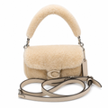 A beige sheepskin handbag with a curved top handle and a matching shoulder strap, featuring a silver-tone 'C' logo on the front. Pre-Owned Coach Tabby 18 Shearling Shoulder / Crossbody Bag – Cream