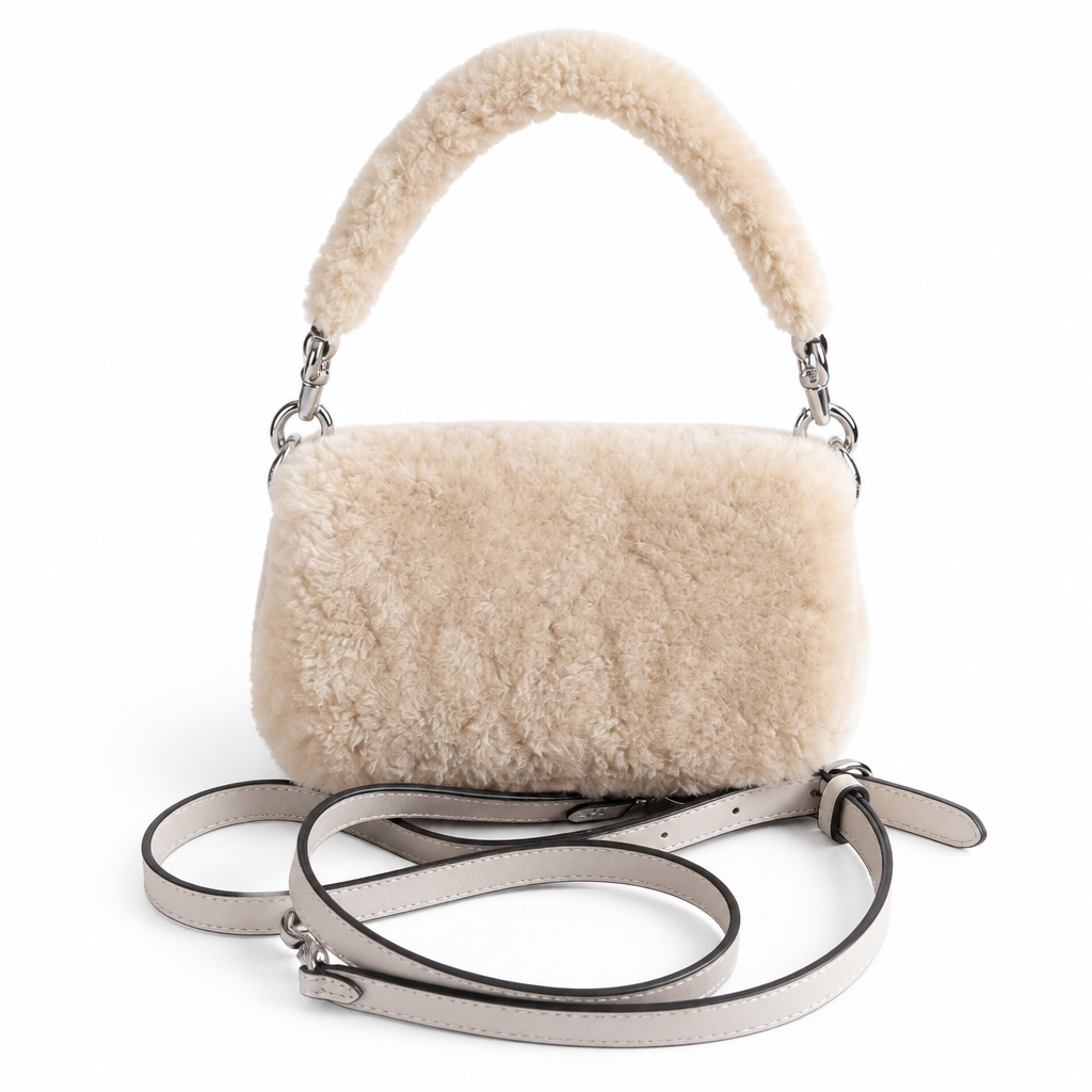 A fluffy cream-colored sheepskin handbag with a matching curved top handle and a light gray leather shoulder strap, displayed on a clean white background. Pre-Owned Coach Tabby 18 Shearling Shoulder / Crossbody Bag – Cream