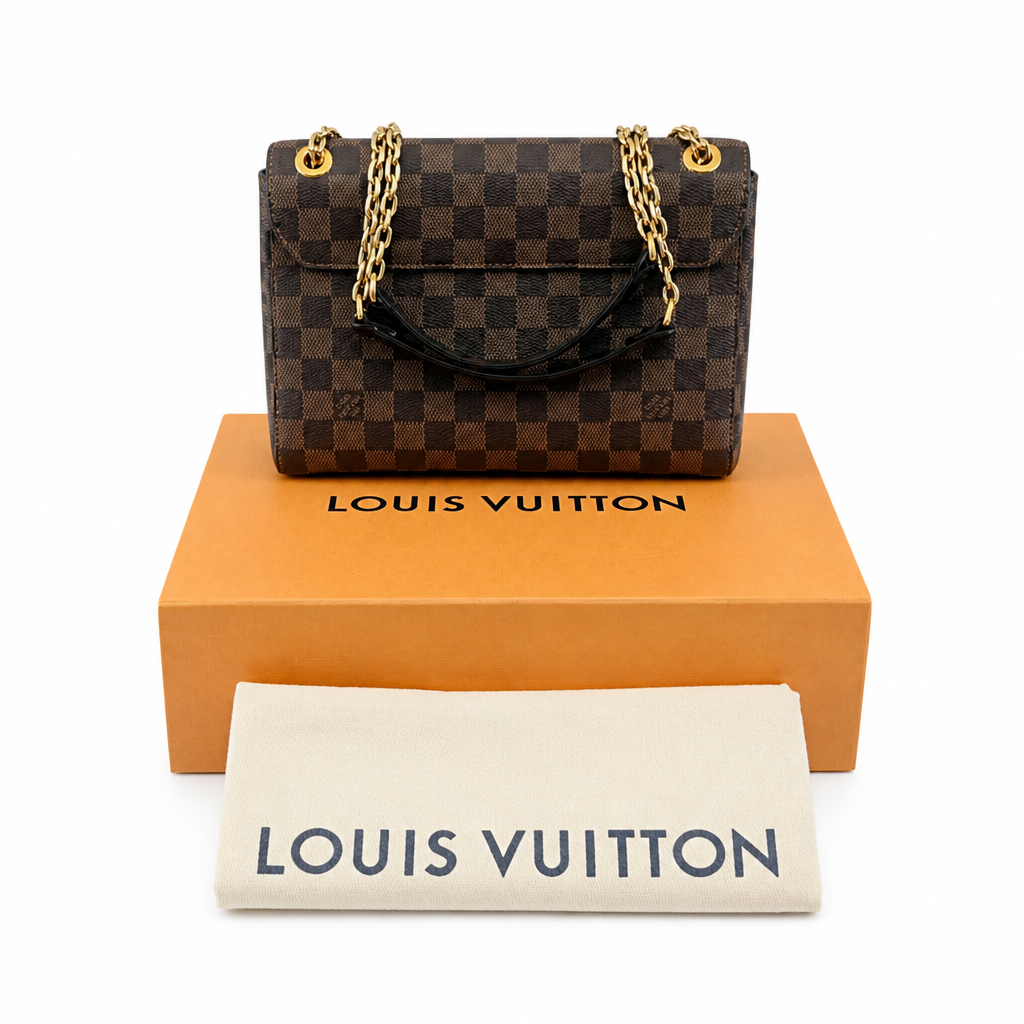 A Louis Vuitton handbag in Damier Ebene canvas, displayed on top of its signature orange box with a white dust bag in front, all on a clean white background. Pre-Owned Louis Vuitton Vavin PM Damier Ebene / Crème – N40113