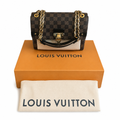 A Louis Vuitton handbag in the Damier Ebene check pattern, displayed on top of its signature orange box with a cream dust bag in front. The bag features gold-tone chain straps and hardware. Pre-Owned Louis Vuitton Vavin PM Damier Ebene / Crème – N40113
