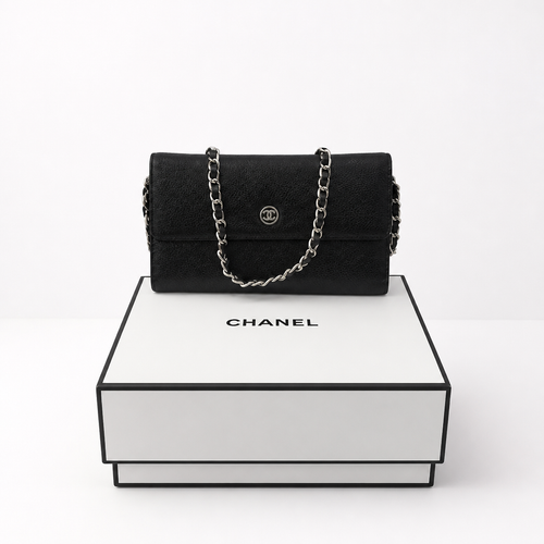 A black Chanel shoulder bag with a silver chain strap and interlocking CC logo, displayed on top of a white Chanel gift box against a clean white background. 