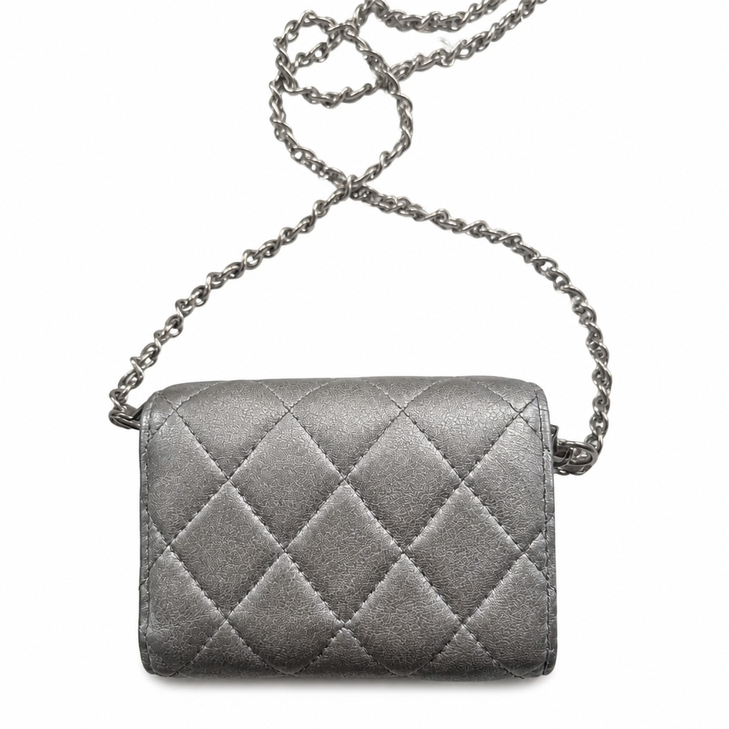 A metallic silver quilted shoulder bag with a diamond-quilted pattern and a matching silver chain strap, shown against a plain white background. Pre-Owned Chanel Metallic Silver Matelassé Mini Chain Wallet / Micro Crossbody