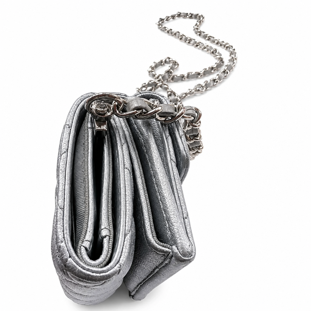A metallic silver quilted purse with a matching silver chain strap, shown from a side profile view on a white background. Pre-Owned Chanel Metallic Silver Matelassé Mini Chain Wallet / Micro Crossbody