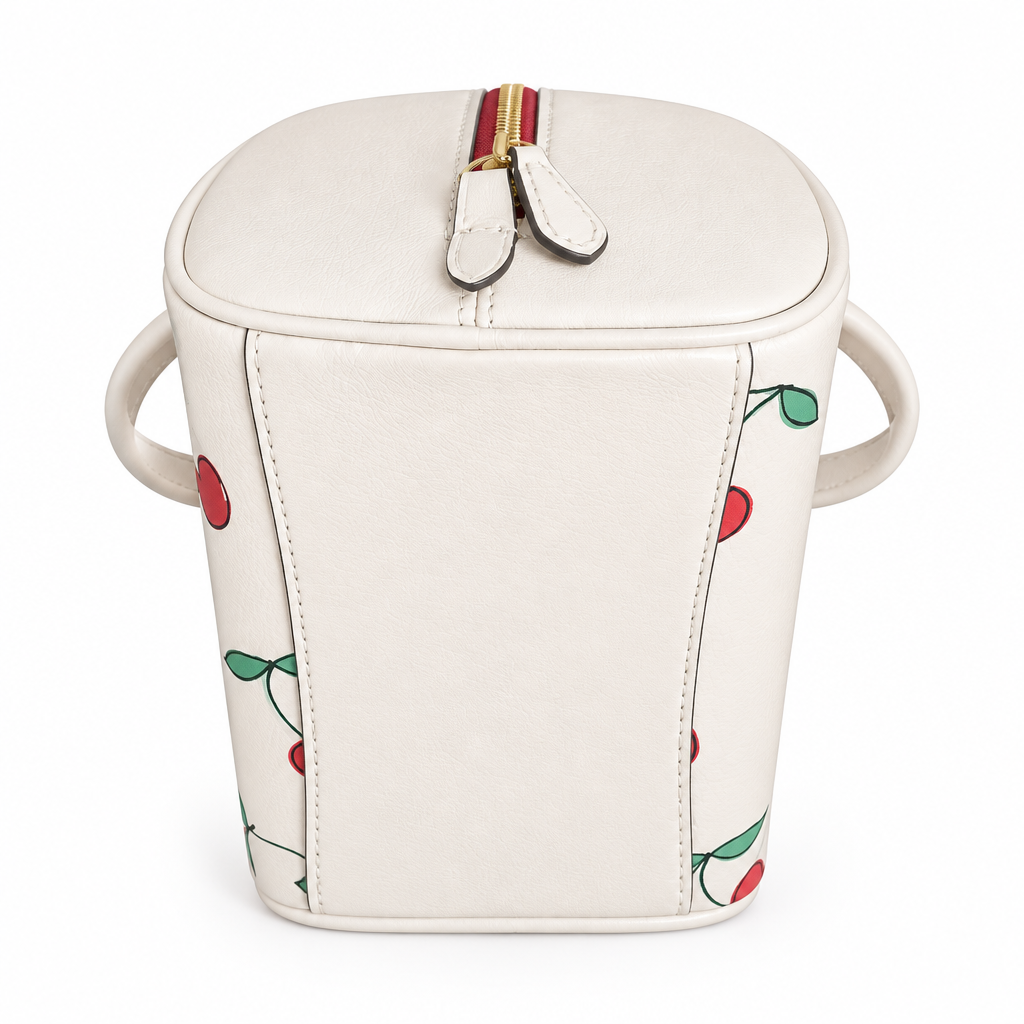 An off-white leather bucket bag with side handles, decorated with a red and green cherry pattern, featuring a top zipper with a leather pull tab. Pre-Owned Coach Sydney Satchel With Heart Cherry Print – CF421