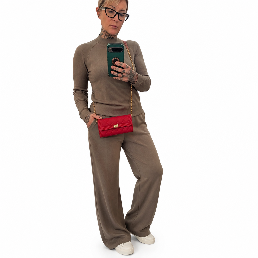 A woman modeling a taupe brown knit matching set consisting of a mock-neck long-sleeve top and wide-leg trousers, styled with a red quilted crossbody bag, black eyeglasses, and white sneakers against a plain white background. Pre-Owned Chanel Boy Wallet on Chain – Fuchsia Pink Caviar Leather – Gold Hardware