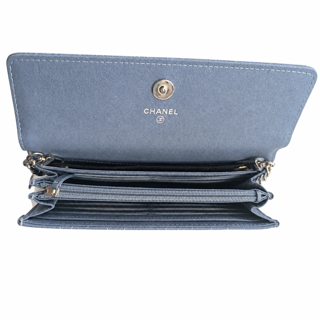An open Chanel wallet in a dusty blue textured leather, showing multiple card slots, zip compartments, and the gold-tone CHANEL logo on the inside flap. Pre-Owned Chanel Camellia Studded Wallet on Chain WOC – Blue Lambskin