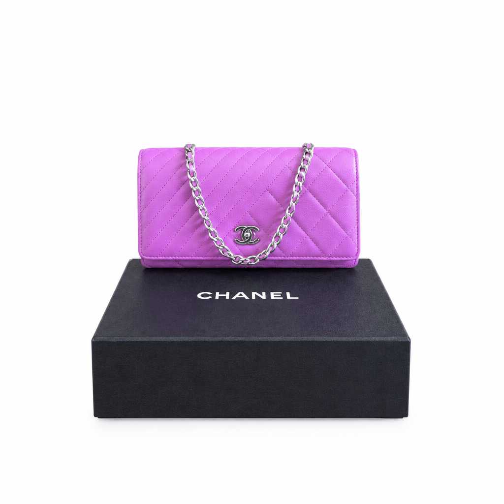 A Chanel quilted flap handbag in bright purple with a silver chain strap and interlocking CC logo, displayed on top of a black Chanel box against a white background. Pre-Owned Chanel Quilted Wallet on Chain WOC – Pink/Purple Lambskin – Silver Hardware