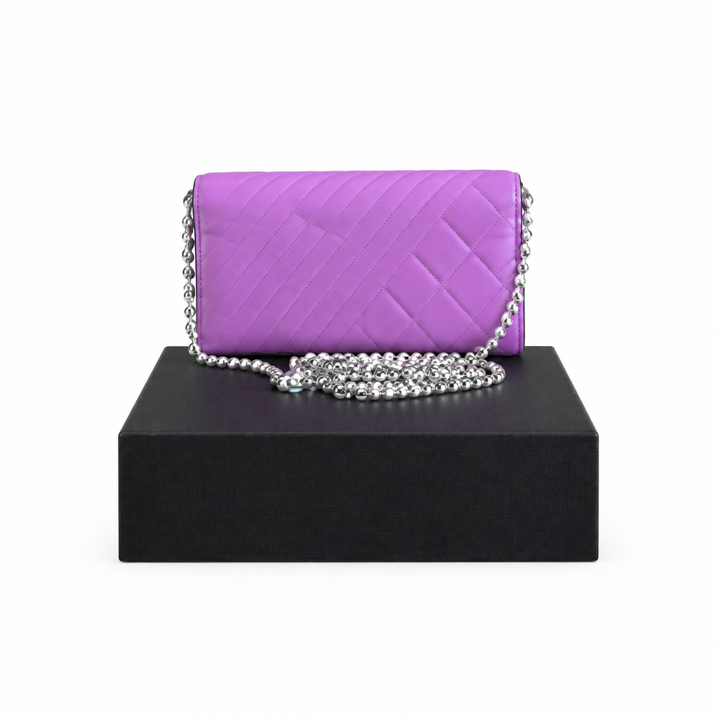 A purple quilted leather shoulder bag with a silver chain strap, displayed on a black rectangular box against a white background. Pre-Owned Chanel Quilted Wallet on Chain WOC – Pink/Purple Lambskin – Silver Hardware