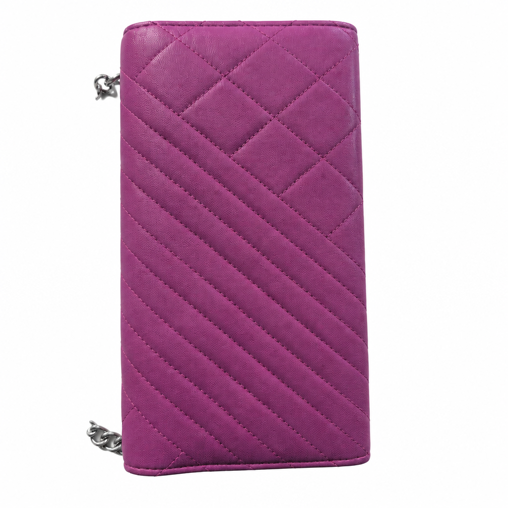 A magenta quilted zip-around wallet with diagonal stitching and silver-tone chain accents, shown against a plain white background. Pre-Owned Chanel Quilted Wallet on Chain WOC – Pink/Purple Lambskin – Silver Hardware