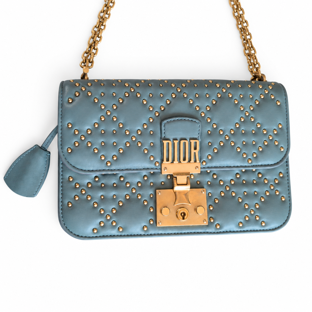 A light blue quilted leather shoulder bag with gold studs, a gold chain strap, and a gold clasp closure, shown on a plain white background. Pre-Owned Christian Dior Small DiorAddict Cannage Studded Flap Bag – Light Blue Lambskin