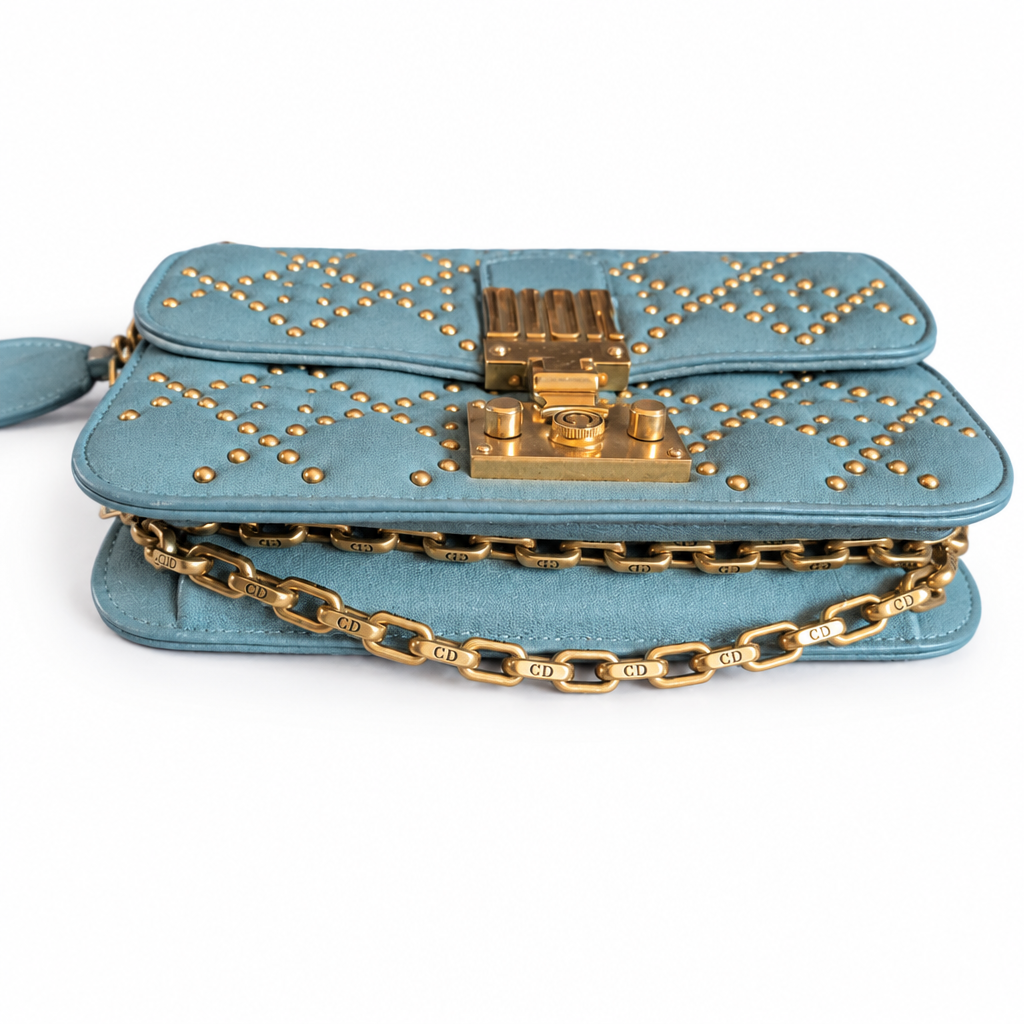 A blue suede shoulder bag with gold-tone hardware, featuring a decorative studded pattern on the flap, a central clasp, and a chain strap engraved with 'CHLOE'. Pre-Owned Christian Dior Small DiorAddict Cannage Studded Flap Bag – Light Blue Lambskin