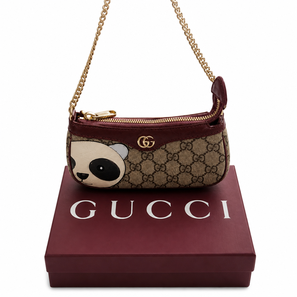 A Gucci shoulder bag with a panda face applique on a beige GG monogram canvas, resting on top of a burgundy Gucci box. The bag features a gold chain strap and a gold-tone GG logo on a clean white background. Pre-Owned Gucci GG Supreme Ophidia Panda Mini Chain Shoulder Bag
