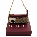 A Gucci shoulder bag with a panda face applique on a beige GG monogram canvas, resting on top of a burgundy Gucci box. The bag features a gold chain strap and a gold-tone GG logo on a clean white background. Pre-Owned Gucci GG Supreme Ophidia Panda Mini Chain Shoulder Bag