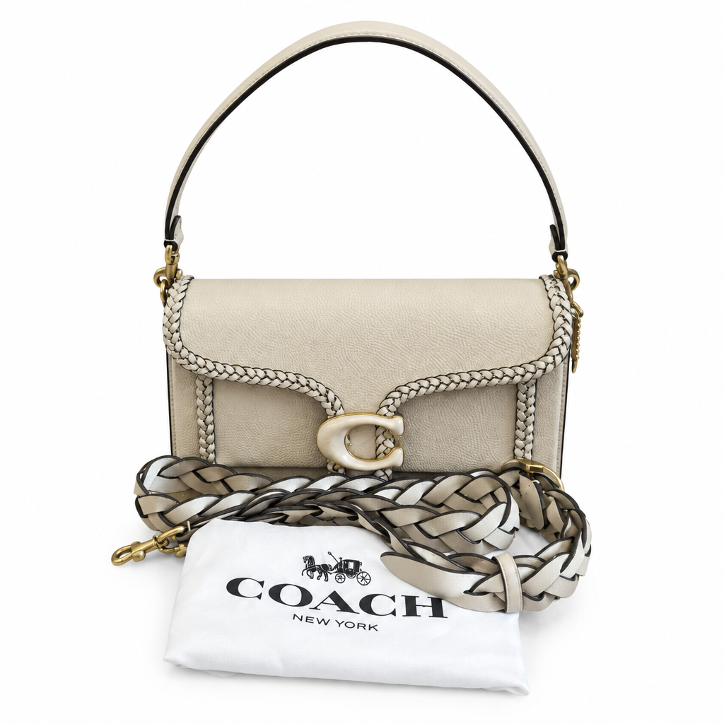 Coach New York cream-colored pebbled leather shoulder bag with a braided leather strap detail, gold-tone hardware, and a white branded dust bag, shown on a white background. Pre-Owned Coach Tabby Braided Leather Shoulder Bag – Beige
