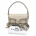Coach New York cream-colored pebbled leather shoulder bag with a braided leather strap detail, gold-tone hardware, and a white branded dust bag, shown on a white background. Pre-Owned Coach Tabby Braided Leather Shoulder Bag – Beige
