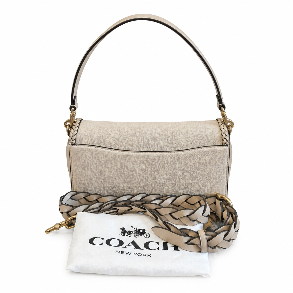 A Coach shoulder bag in light beige textured leather with gold-tone hardware, shown with a matching patterned scarf and a white Coach New York dust bag on a white background. Pre-Owned Coach Tabby Braided Leather Shoulder Bag – Beige