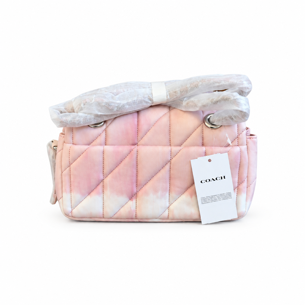 A Coach quilted shoulder bag in a pink and white tie-dye pattern, wrapped in protective plastic on the handle with a white COACH hangtag attached. Pre-Owned Coach Tabby 20 Quilted Nappa Leather Shoulder Bag – Pink & White Ombré