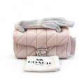 A Coach quilted shoulder bag in pink with silver-tone hardware, shown with a white dust bag printed with the Coach logo in front of it on a white background. Pre-Owned Coach Tabby 20 Quilted Nappa Leather Shoulder Bag – Pink & White Ombré