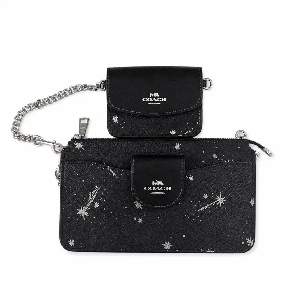 A Coach black starry print pouch set featuring a larger zip-around card holder with a front flap and a smaller matching coin purse, both with silver-tone hardware and chain details, on a white background. Pre-Owned Coach Black Celestial Print Crossbody Pouch Set – Excellent Condition
