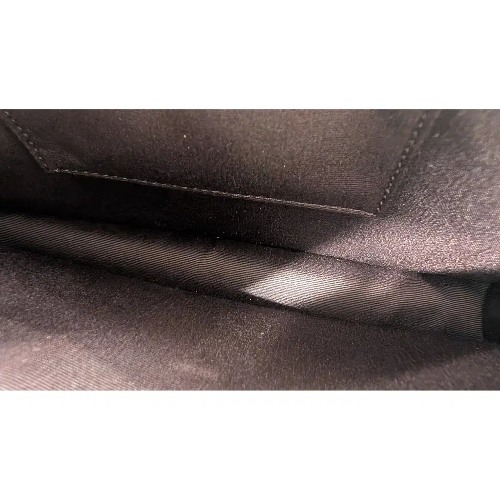 Close-up of a dark brown textured fabric interior with visible stitching and a satin-like fold. Pre-Owned Coach Black Celestial Print Crossbody Pouch Set – Excellent Condition