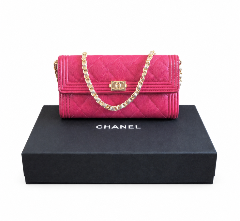 A Chanel quilted flap shoulder bag in vibrant pink, displayed on top of its black branded box against a white background. Chanel_Boy_Wallet_on_Chain_Fuchsia_Pink_Caviar_Leather_Gold_Hardware