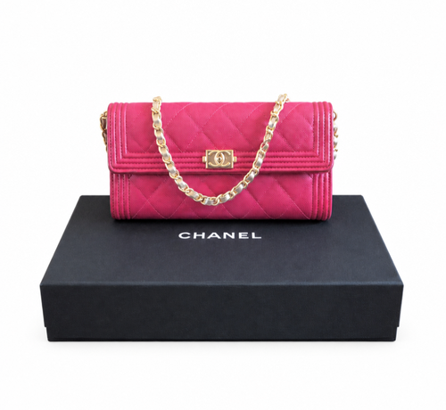 A Chanel quilted flap shoulder bag in vibrant pink, displayed on top of its black branded box against a white background. Chanel_Boy_Wallet_on_Chain_Fuchsia_Pink_Caviar_Leather_Gold_Hardware