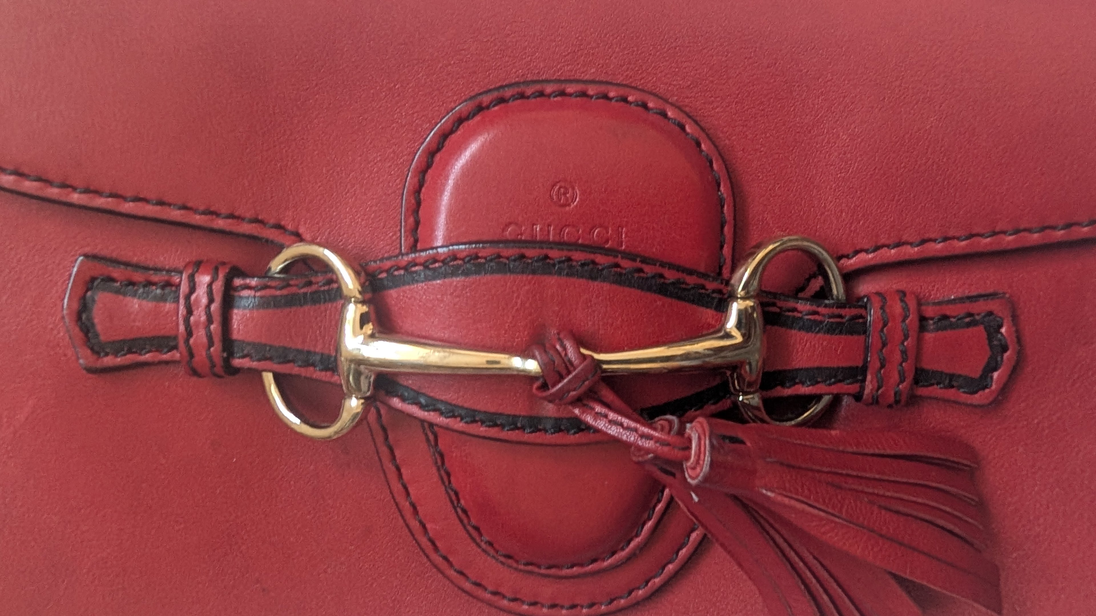 Close-up of a red Gucci handbag with a gold clasp and tassel.