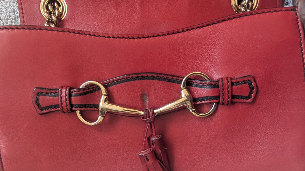Red leather bag with a gold and red bridle detail showing marks