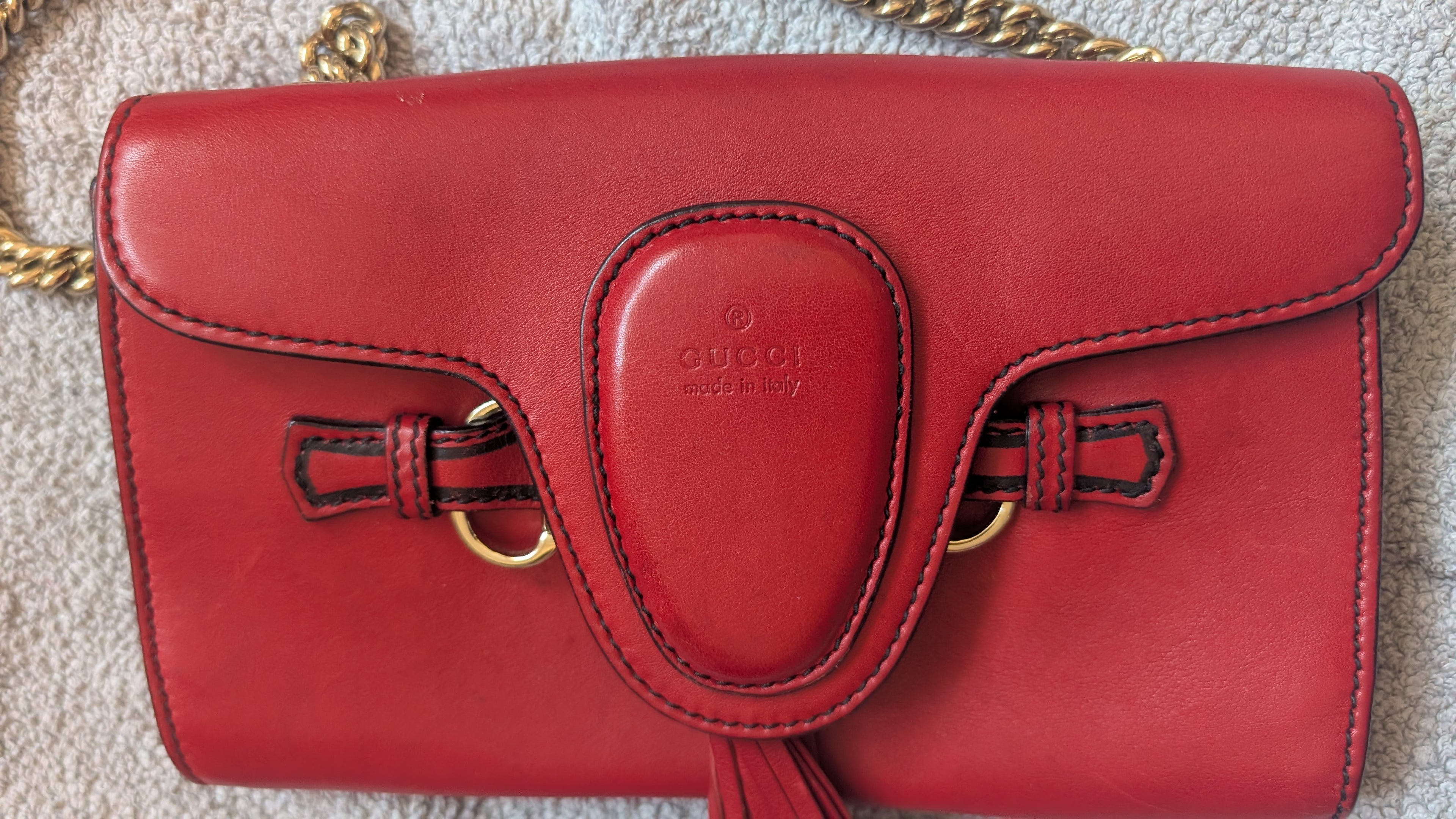 Red handbag with a visible Gucci brand logo on a textured surface
