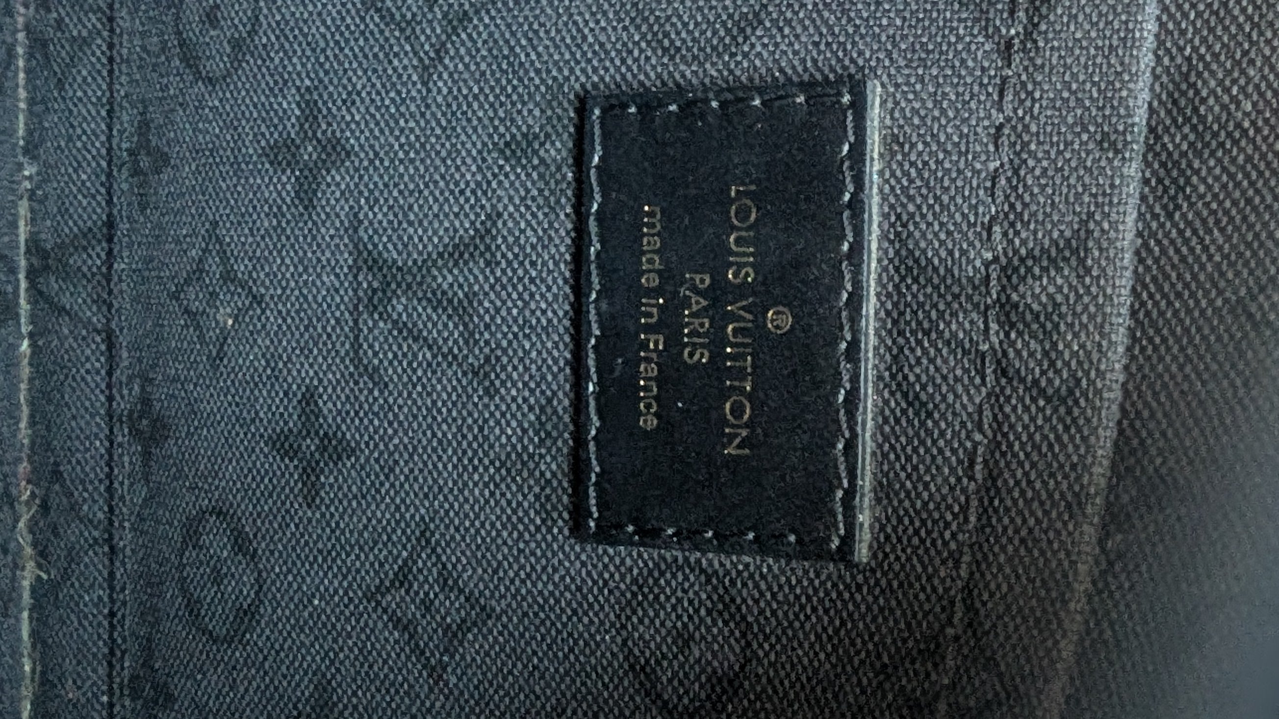 Close-up of inside of Louis Vuitton bag with monogram pattern and visible brand logo.