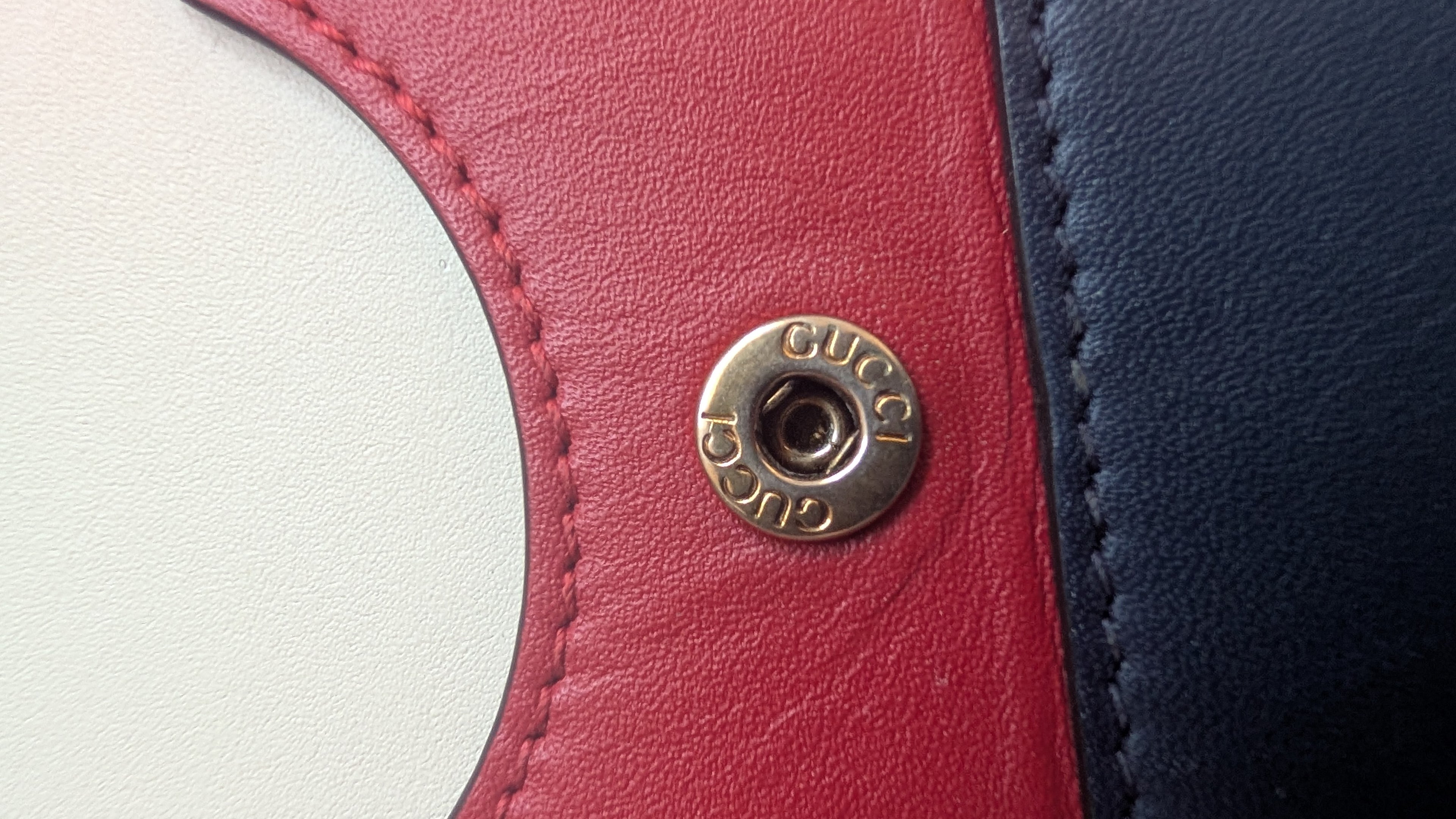 Close-up of a Gucci logo on a red and blue leather product.