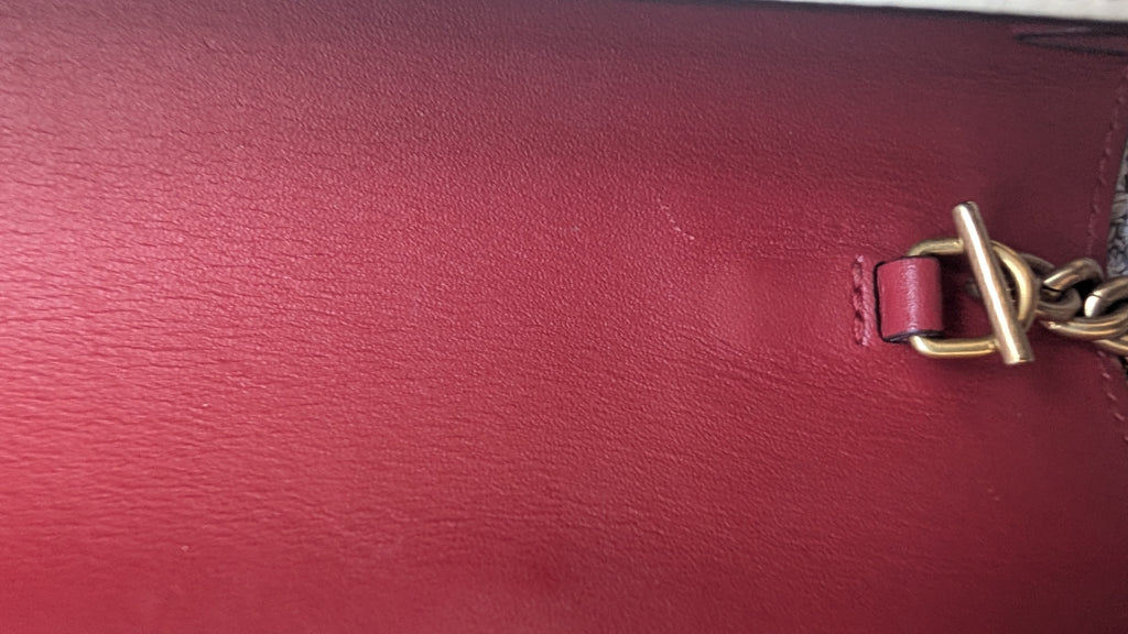 Close-up of a red leather surface with a gold chain detail Pre-owned Gucci Queen Bee On Removable Chain