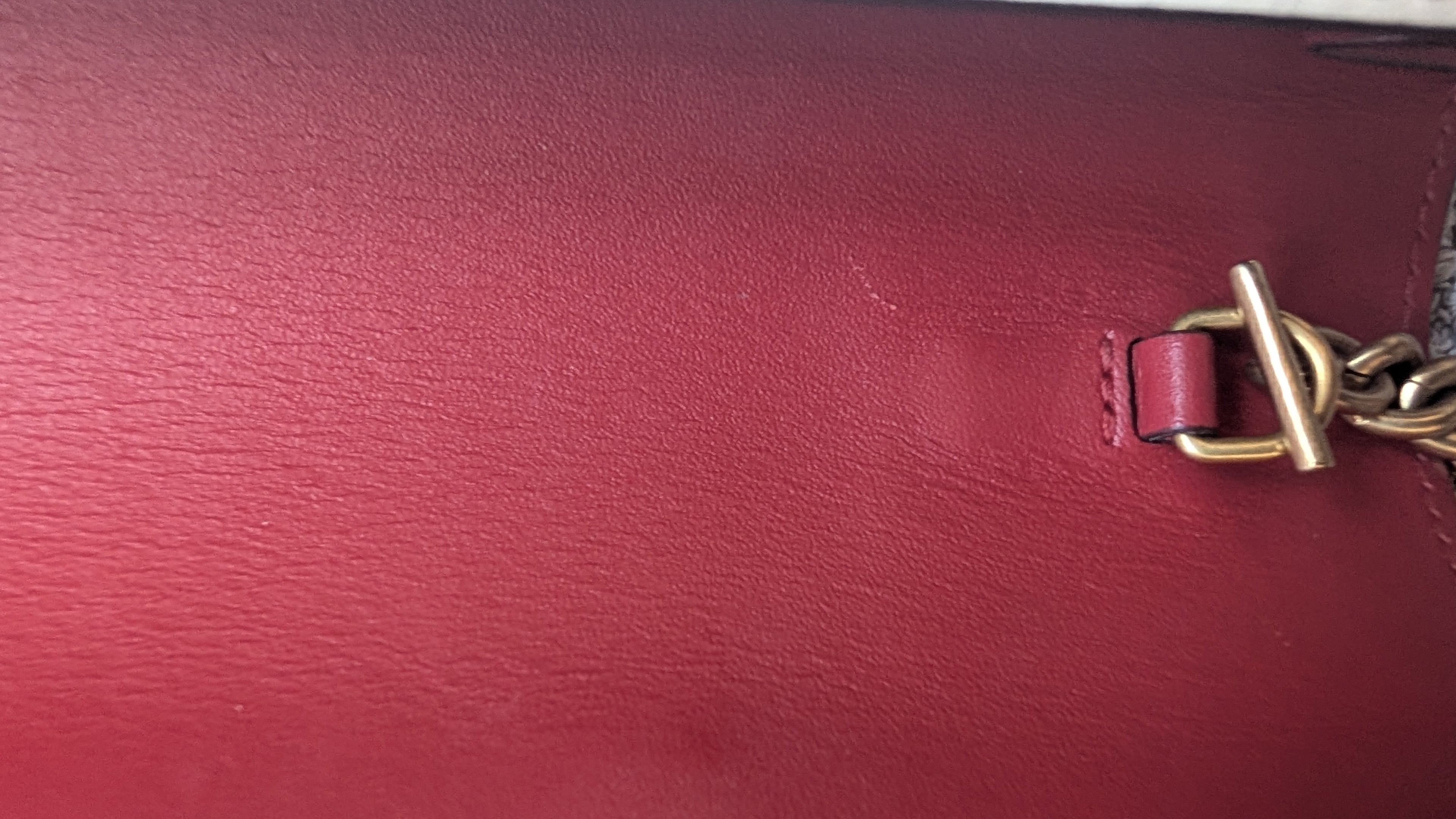 Close-up of a red leather surface with a gold chain detail Pre-owned Gucci Queen Bee On Removable Chain