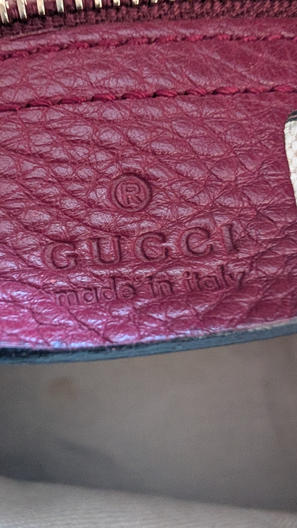 Close-up of a Gucci wallet with embossed logo and 'Made in Italy' text.