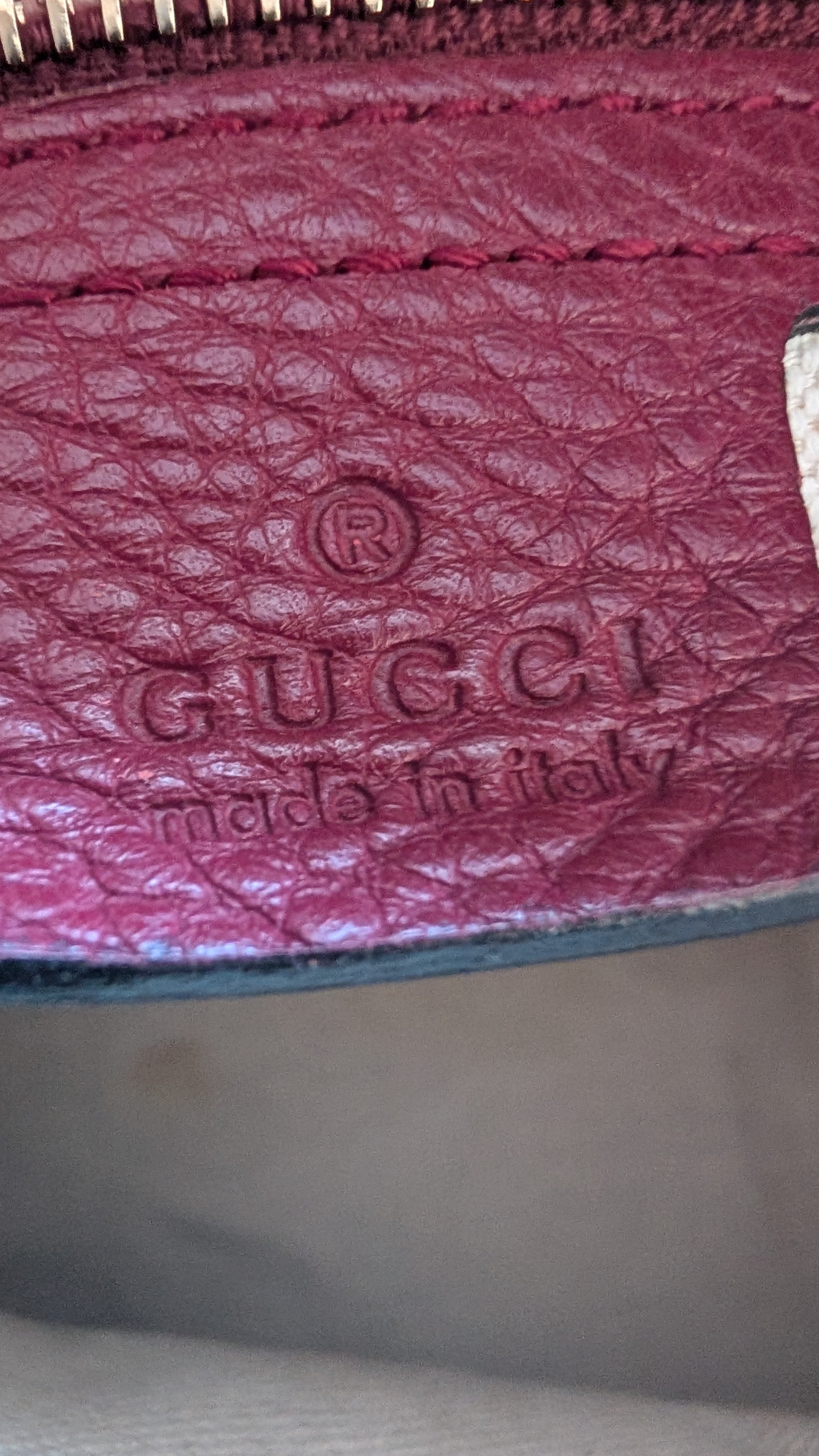 Close-up of a Gucci wallet with embossed logo and 'Made in Italy' text.