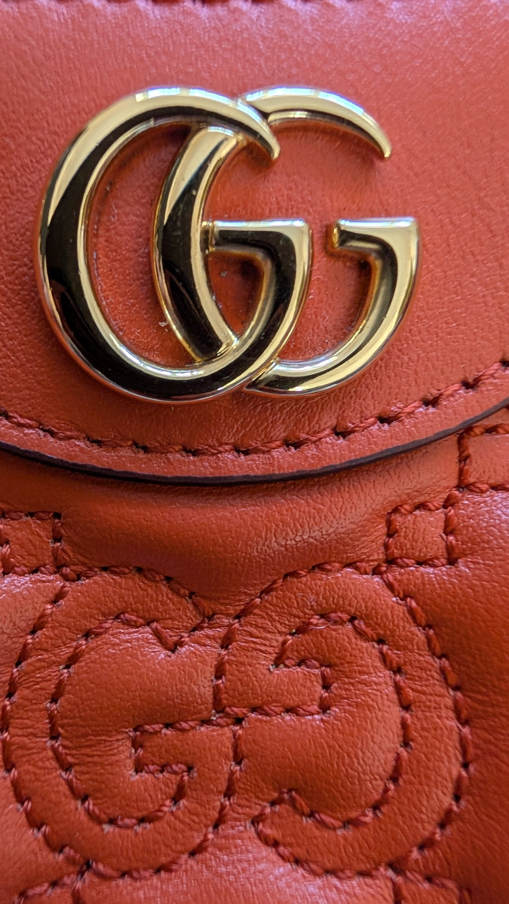 Close-up of a orange Gucci handbag with gold logo.Pre-owned Gucci GG Quilted Matelasse Leather Mini Shoulder Bag In Orange