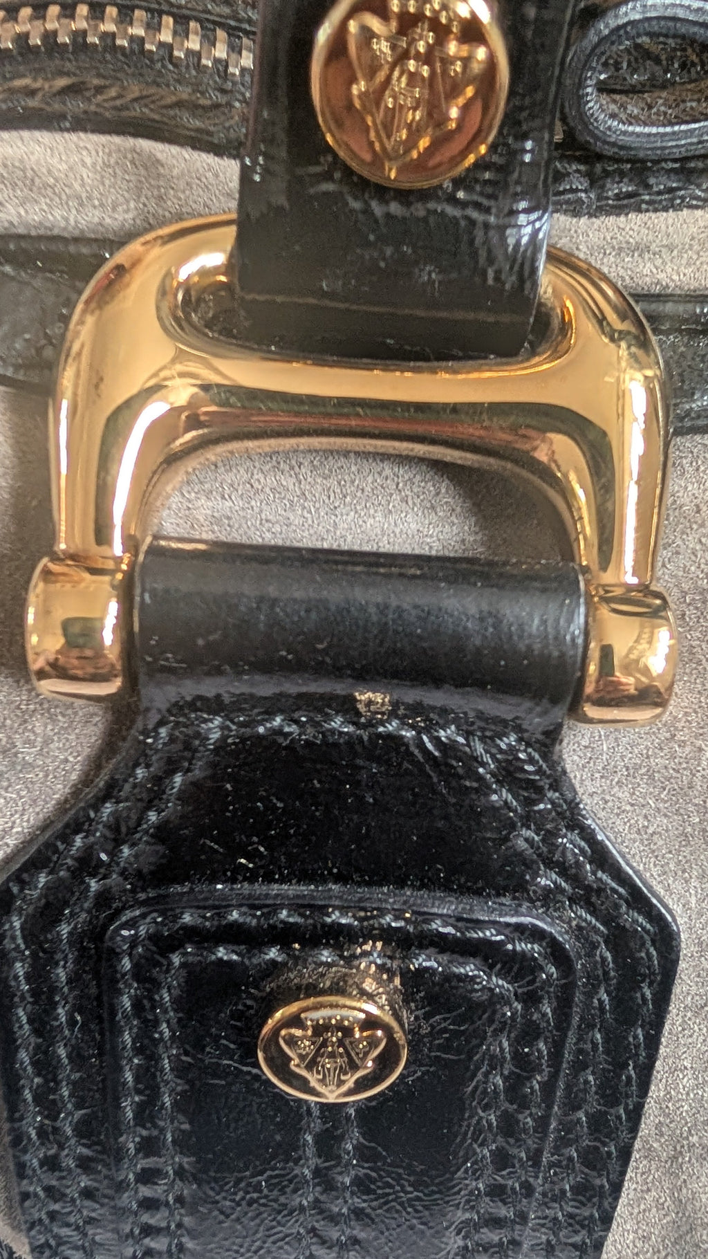 Close-up of a black textured handbag with gold hardware on a gray background Pre-Owned Gucci Grey Suede Aviatrix Boston Bag