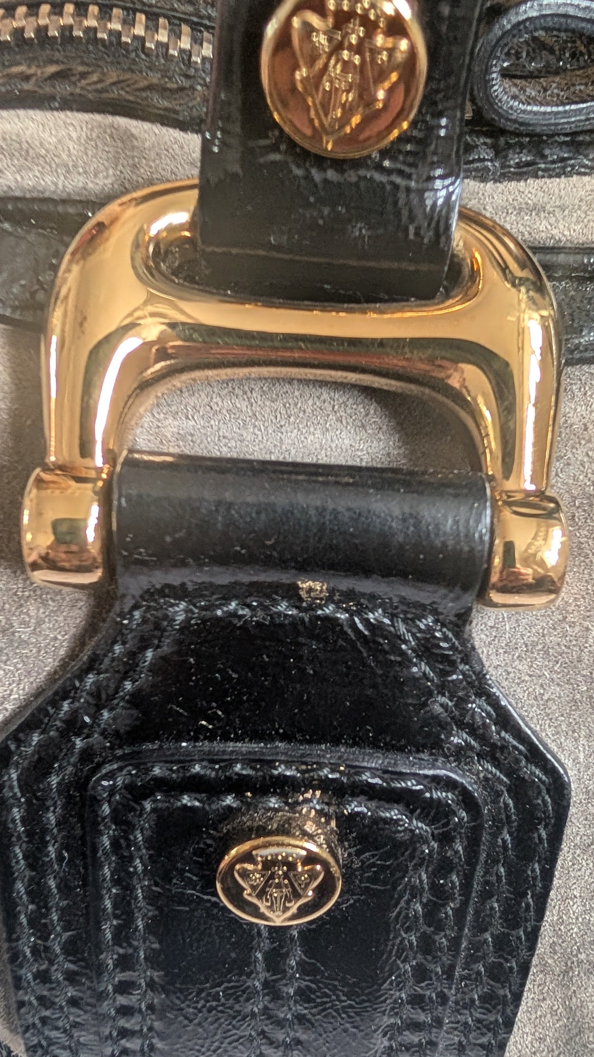 Close-up of a black textured handbag with gold hardware on a gray background Pre-Owned Gucci Grey Suede Aviatrix Boston Bag