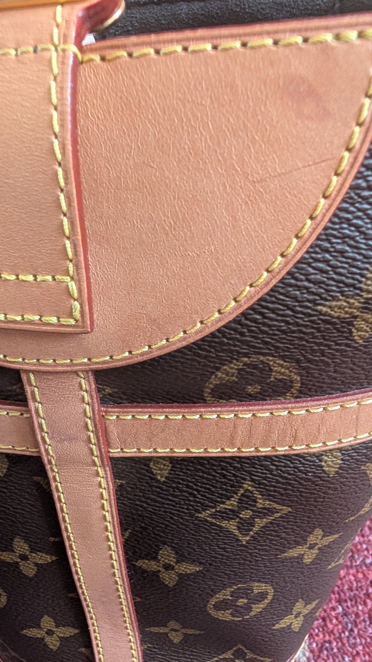 Close-up of a Louis Vuitton monogram canvas bag with tan leather trim and gold contrast stitching. Pre-Owned Louis Vuitton Duffle Bucket Monogram Canvas - Full Set