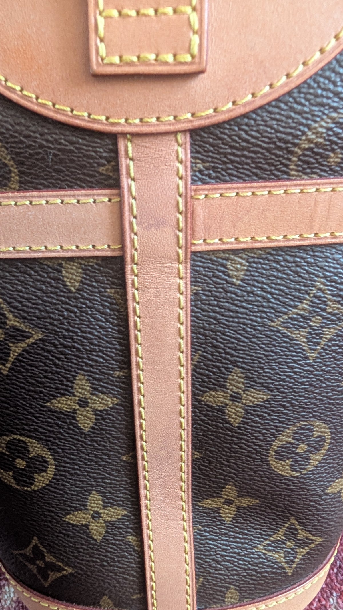 Close-up of a Louis Vuitton monogram canvas bag with tan leather trim and contrast stitching. Pre-Owned Louis Vuitton Duffle Bucket Monogram Canvas - Full Set