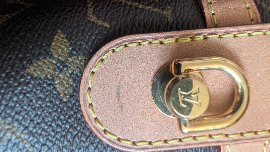Close-up of a Louis Vuitton monogram bag showing the brown coated canvas, tan leather trim, and a gold-tone metal D-ring closure with an LV logo. Pre-Owned Louis Vuitton Duffle Bucket Monogram Canvas - Full Set