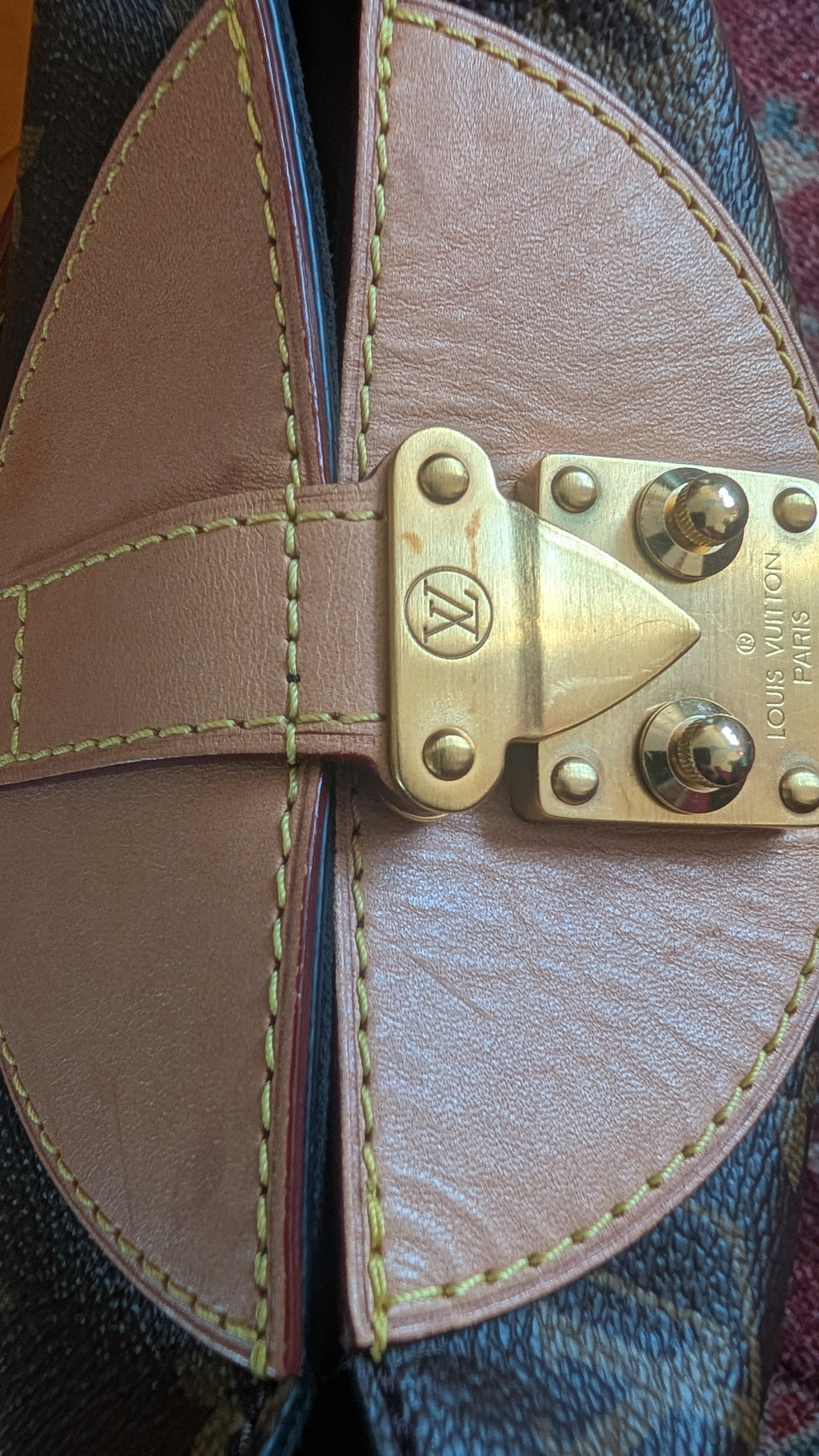Close-up of a Louis Vuitton monogram bag showing the brown leather strap, tan leather interior lining, and a brass-tone metal clasp with the Louis Vuitton monogram and 'MADE IN FRANCE' text. Pre-Owned Louis Vuitton Duffle Bucket Monogram Canvas - Full Set