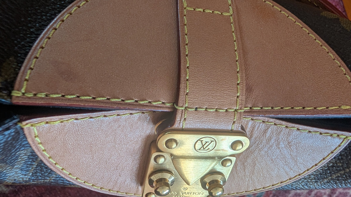 Close-up of a Louis Vuitton monogram bag showing the interior flap construction with tan leather, yellow stitching, and a brass-tone LV clasp. Pre-Owned Louis Vuitton Duffle Bucket Monogram Canvas - Full Set
