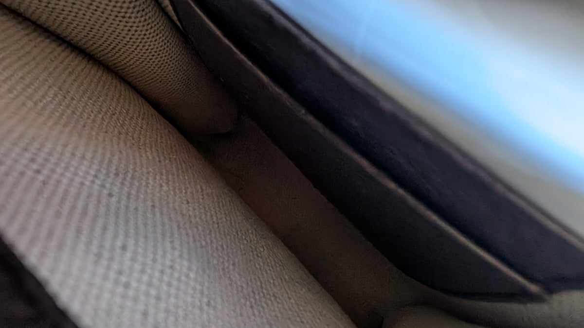 Close-up detail of a textured beige woven fabric item with a dark brown or black stitched edge. Pre-Owned Gucci x Ken Scott "What's Inside" Crossbody Phone Holder – GG Supreme Canvas – Full Set