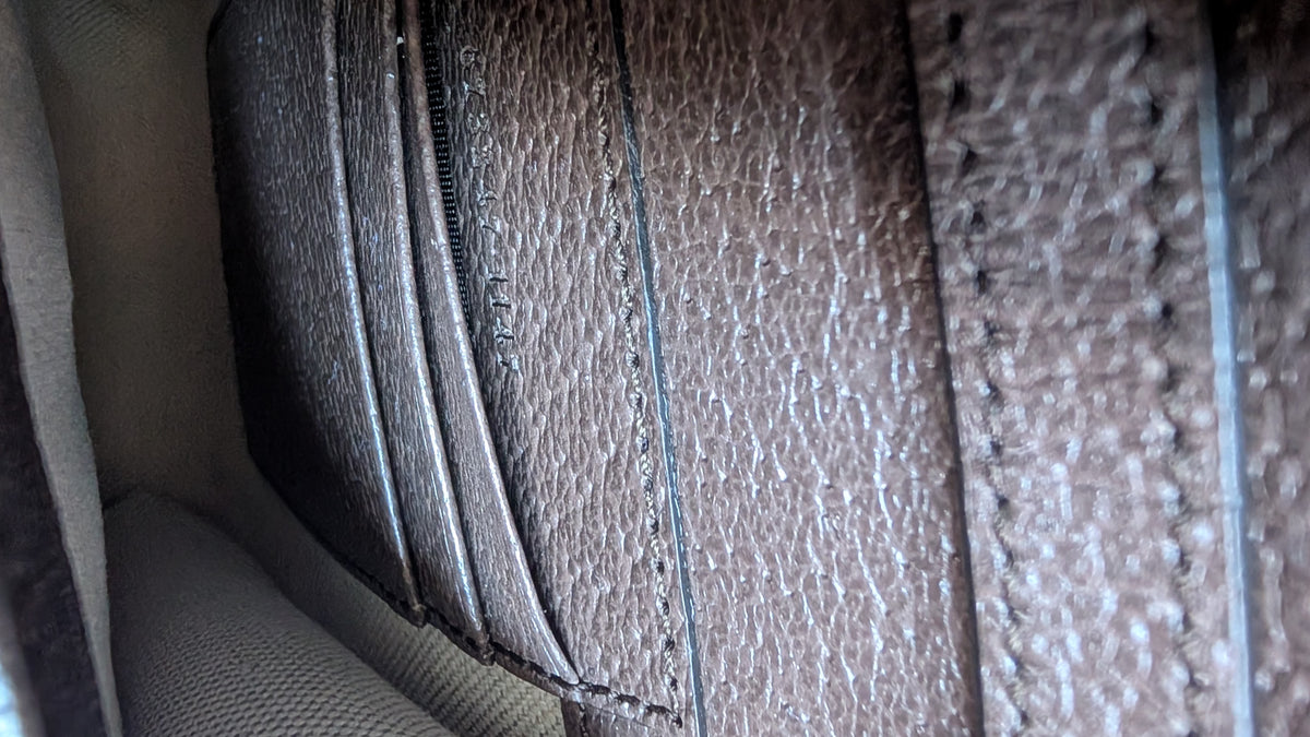 Close-up of a brown textured leather wallet showing card slots, stitching, and interior lining. Pre-Owned Gucci x Ken Scott "What's Inside" Crossbody Phone Holder – GG Supreme Canvas – Full Set